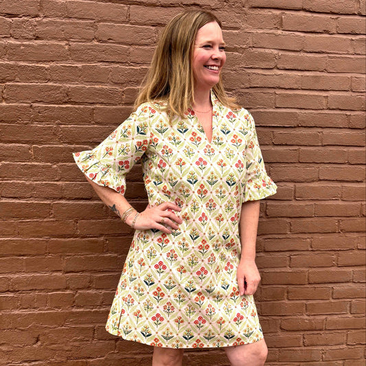 Woman wearing a floral dress standing against a brick wall